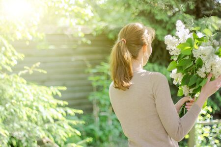 Beautiful young tender girl with a bouquet of flowers. Charming young lady with a bouquet of lilacs.