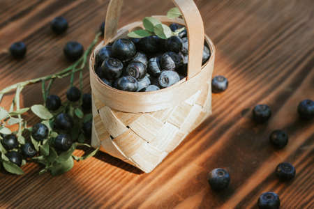 blueberries in a small basket of birch bark on a wooden background. the crop of berries, vitaminsの写真素材