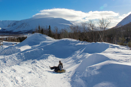 father and child ride snow tubing from the mountain. winter fun on a frosty clear snowy day. joint family vacationの写真素材