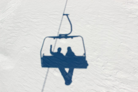 shadows on the snow of two snowboarders who go up the mountain on a ski lift. healthy lifestyle, joint outdoor recreation on a winter dayの写真素材