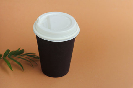 paper Cup with lid for coffee or hot drinks with you on a brown backgroundの写真素材