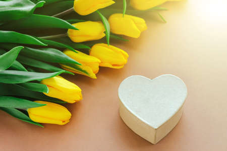 yellow tulips and gift box in the shape of a heart on a beige background. Background of mother Day, Valentine day. Still life, Flat layの写真素材
