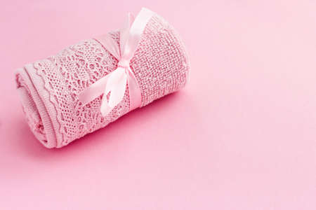 gift pink towel with a satin ribbon on a pink background. the concept of personal hygiene,...