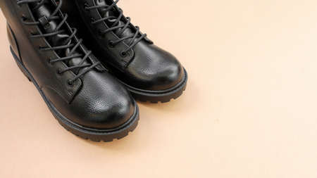 Black leather boots on brown background. Fashionable modern female shoes military style.の写真素材