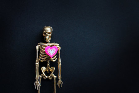 a golden skeleton with a pink heart on a black background. Halloween Concept.の写真素材
