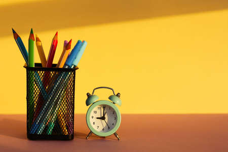 workspace with alarm clock and office supplies on yellow background. Back to school.school tools,...