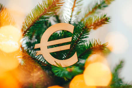wooden Christmas tree toy in the shape of a euro money sign on the background of a Christmas treeの写真素材