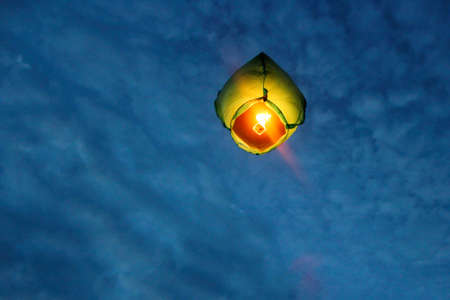 A Chinese lantern flies high into the night sky. Making wishes when releasing a paper flying lantern into the skyの写真素材
