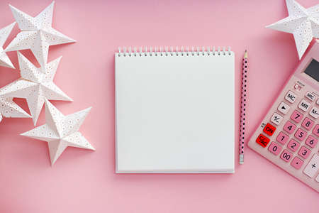 Overhead view working table. on a pink background, a pink calculator, a blank notepad for notes, a...