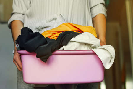 A woman with a basket of dirty laundry for washing. cleaning the house. home routine workの写真素材