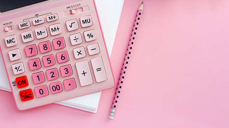Overhead view working table. on a pink background, a pink calculator, a blank notepad for notes, a pencilの写真素材