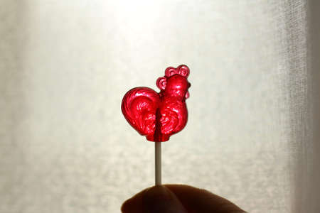 Transparent lollipop red cockerel on a stick.