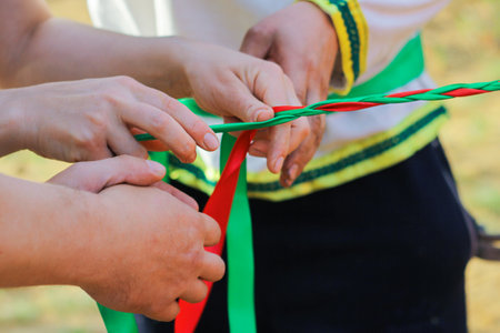 hands braid green and red ribbons. joint, collective work.の写真素材