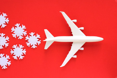 a plane with snowflakes on a red background. travel concept for New Year holidays or winter resortsの写真素材