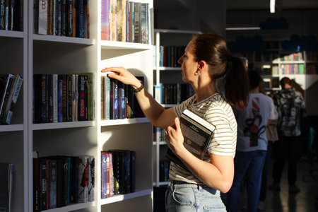 A woman in the library in search of a book. the concept of education, visits to the reading roomの写真素材