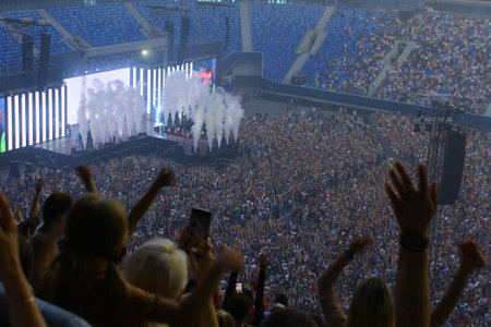 People at the concert. Audience with hands raised at a music festival and lights streaming down from...