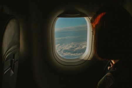 view from the window of the plane. a woman looks at the clouds. travel, tourism, adventure.の写真素材