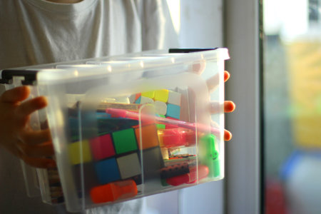 the child holds a box with educational games, puzzles, pencils. preparation for a creative activityの写真素材