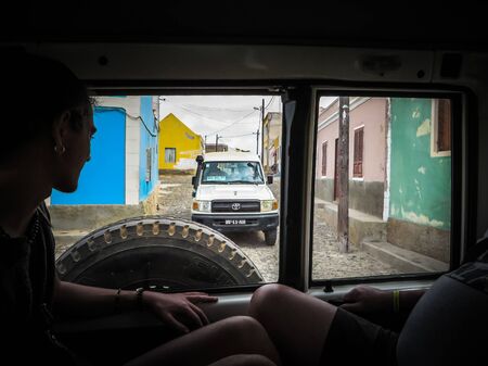 Povoacao Velha, Boa Vista, Cape Verde, Africa - February 9, 2018: View through the rear window of a vehicle onto a moving off-road vehicle through the village, tourists in the foregroundのeditorial素材