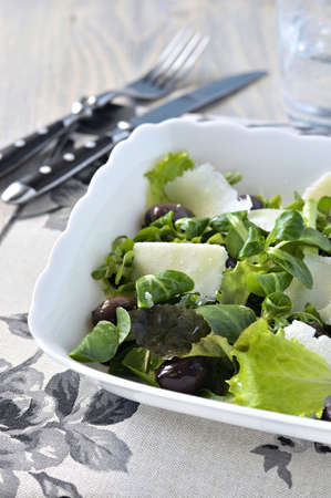 Mesclun salad with olives and Grana Padano cheese in white salad bowl  の写真素材