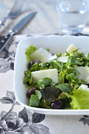 Mesclun salad with olives and Grana Padano cheese in white salad bowl  の写真素材