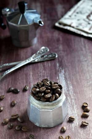 Coffee pot filled with roasted coffee beans, decorated with beautiful spoons and napkin with coffee ornament  の写真素材