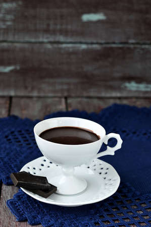 Hot chocolate in a white cup and saucer elegant with chocolate chips on a blue napkin   Still life 