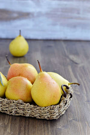 Ripe pears in a basket on a wooden table  の写真素材