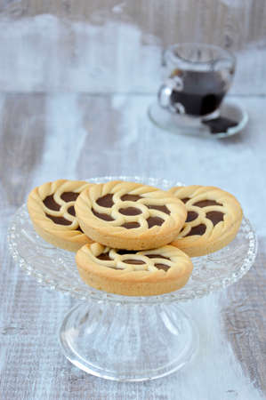 Crostata with Nutella cream - Italian dessert  on a cake stand on a light wooden table, a cup of coffee の写真素材