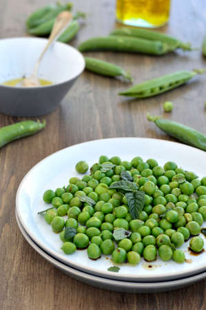 Salad of fresh peas with mint on the plate on a wooden table の写真素材
