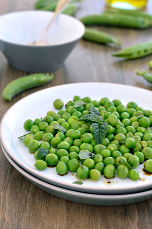 Salad of fresh peas with mint on the plate on a wooden table の写真素材