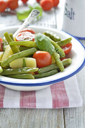 Summer potato salad with fresh green beans, cherry tomatoes, basil in a cup on a wooden table  Selective focus  の写真素材