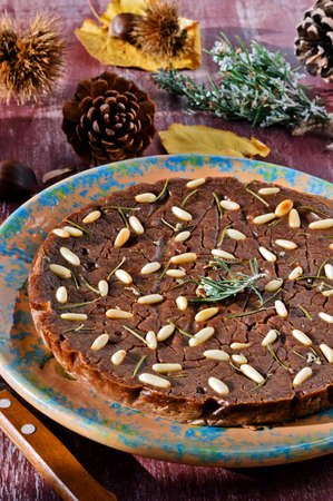 Castagnaccio. Typical of traditional Tuscan Italian cake made with chestnut flour on a colored ceramic plate. Decorated with fresh rosemary, chestnuts.の写真素材