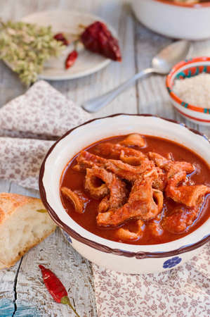 Tripe soup with tomatoes, spicy chili, oregano, Pecorino cheese in a ceramic bowl on a wooden table. Italian food, South Italy.の写真素材
