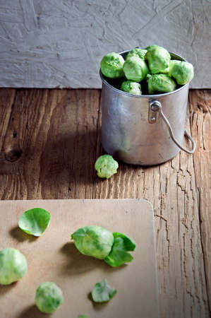 Still life of fresh green Brussels sprouts in a metal container on a wooden background. Selective focusの写真素材