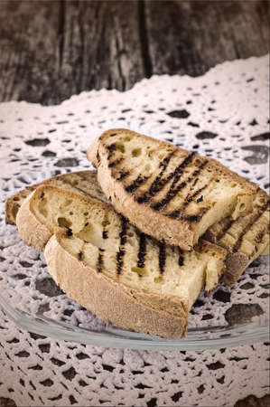 Baked grilled slices of rustic bread for cooking Italian snack (bruschetta) on a white napkin on a...