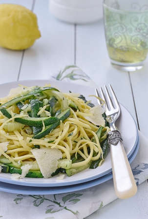 Zucchini Spaghetti alla chitarra with lemon juice and Parmesan cheese on a blue plate.の写真素材