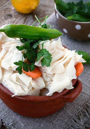 Raw Tripe with Vegetables and Seasoning: Carrots, Peppers, Parsley, Basil in Rustic Ceramic Bowl on a Wooden Backgroundの写真素材
