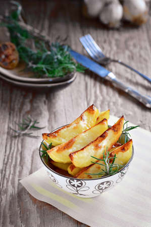French Fries. Fried Potatoes. Baked Potato Wedges, Slices of Baked Potatoes with Garlic and Rosemary. Rustic Food Styleの写真素材