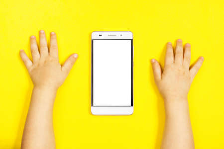Smartphone in the hands of a child on the yellow backstage.の写真素材