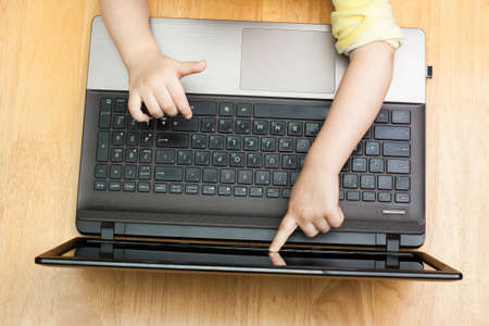 Children's hands and a laptopon the table. The concept education, online communication, early development, technologyの写真素材
