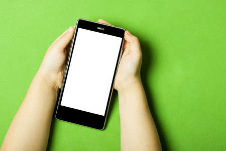 Smart phone in the hands of a child on the greenery backstage. The concept of necessary things a little girl, technology for children. Flat flyの写真素材