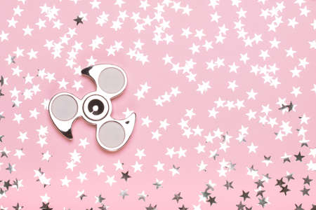 Silvery spinner on a pink background with stars. The concept of trend toys, dreams, fashionの写真素材