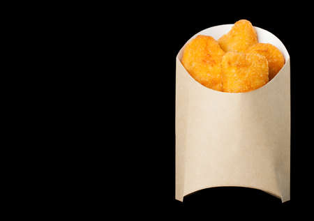 Delicious nuggets in kraft box isolated on a black background. The concept of fast food, delicious food. Photos can be used to create a menu or advertisement. Place for text. Flat flyの写真素材