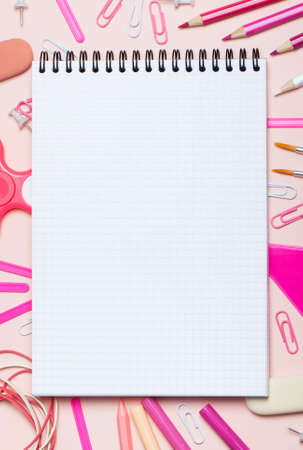 School supplies of pink and white colors on a pink background and empty notebook. Female or girlish still life on the topic of school, study, office work.の写真素材