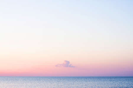 Sea, sky and lonely cloud during summer sunset. Pleasant background with an accent. The concept of a relaxing evening by the sea, relaxation, silence, meditation, contemplationの写真素材