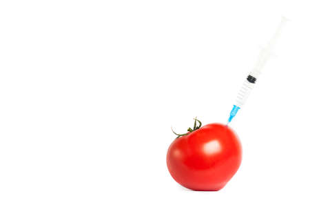 Tomato and syringe with toxins isolated on white background. The concept of GMOs, laboratory studies, toxins, etc.の写真素材
