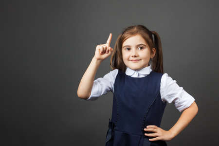 Little girl in a school uniform show a sigh. Attention! Oh, an idea! Do not miss! Copy space. The concept of education, back to school, etc.の写真素材