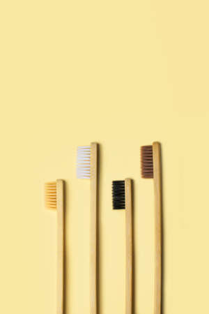 Four eco-friendly bamboo toothbrushes on a yellow background. Zero waste concept, plastic-free,...
