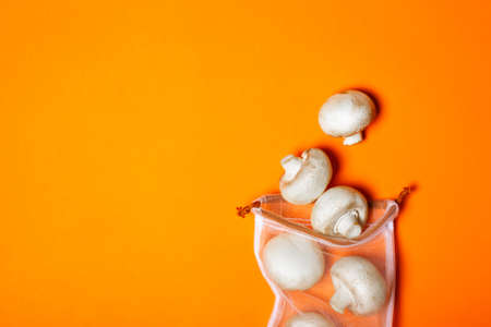 Cute organic champignons in the eco bag on a trendy orange background. Place for text. Zero waste...